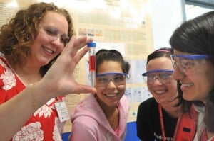 4 women wearing eye protection during laboratory experiment.