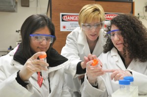 3 women wearing laboratory dress and eye protection.