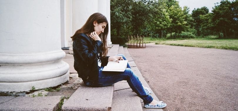 A student sitting and reading a book.