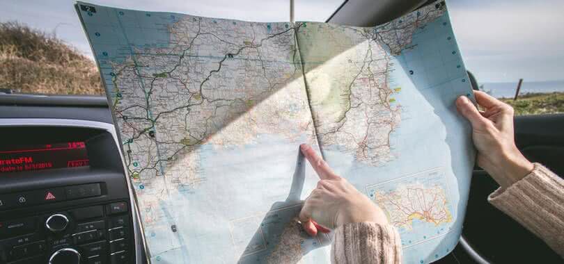 A person holding and pointing at a paper map.