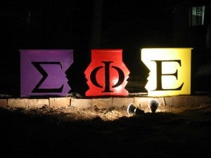 The Sigma Phi Epsilon letters on colorful boxes, illuminated by a spotlight.
