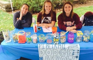 Pi Beta Phi sorority sisters at a table with colorful donoation jars and banner.
