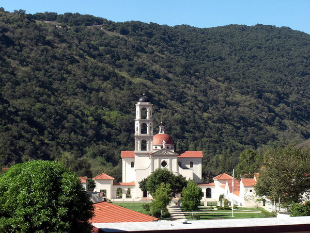 Thomas Aquinas College from afar, surrounded by green trees.