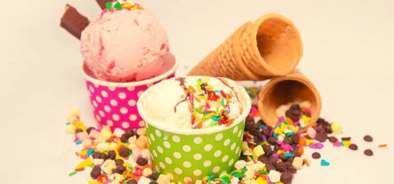 Ice cream in cups, with ice cream cones next to the cups.
