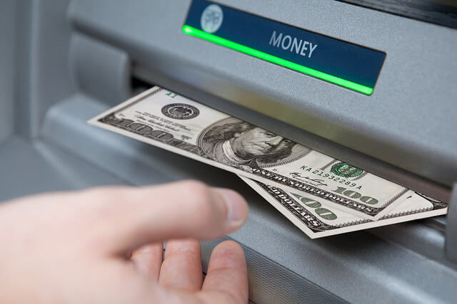Photograph of a person withdrawing money from an ATM.