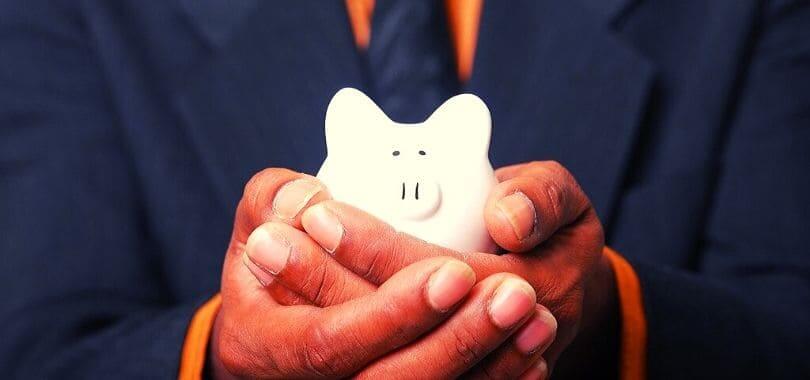 A person holding a white piggy bank in their hands.