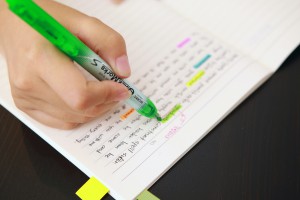 Student marking important notes with a green highlighter.