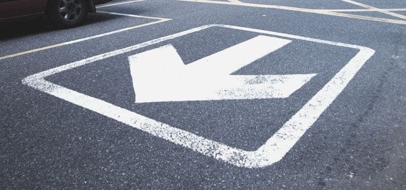 A white arrow pointing away printed on a road.
