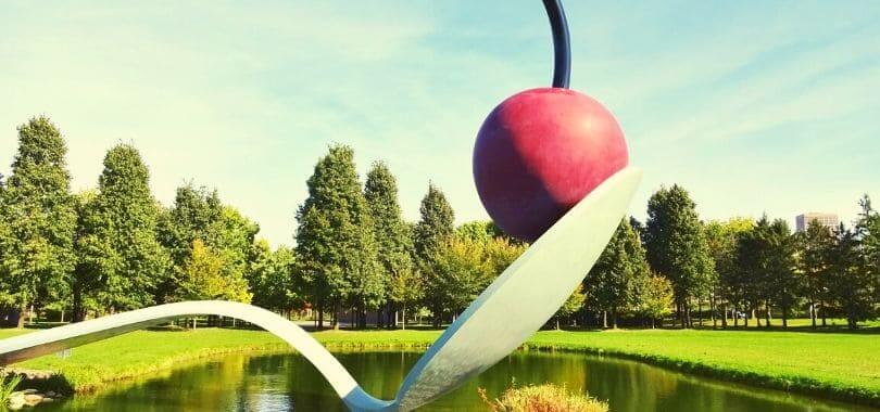 A sculpture of a cherry on top of a spoon.