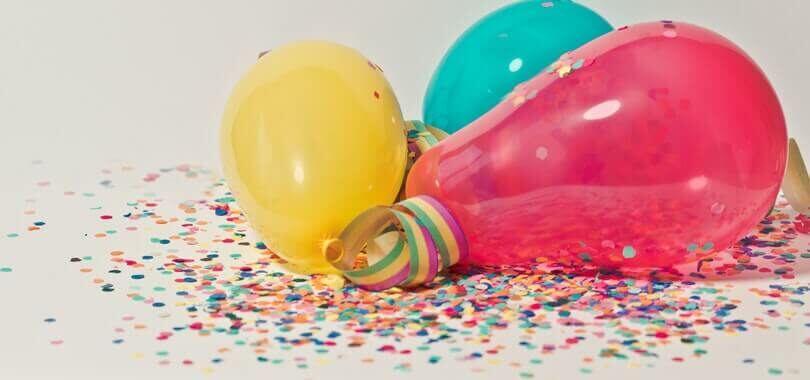 Colorful balloons laying together on top of confetti.