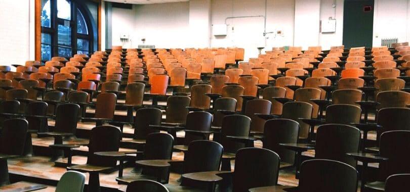 An empty lecture hall filled with brown desks.