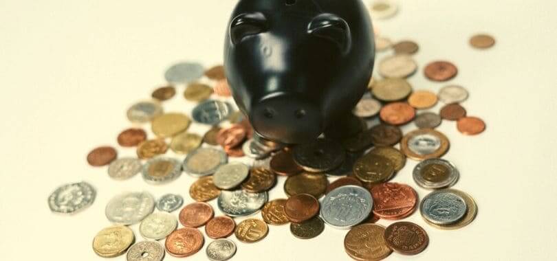 A piggy bank standing on top of a pile of coins.