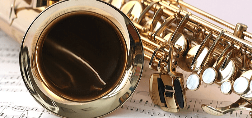 een saxofoon bovenop enkele muziekbladen.