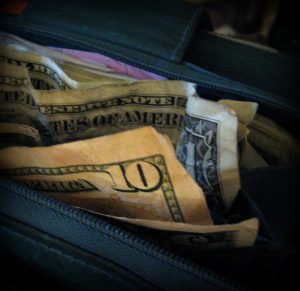 An open black wallet with money inside.