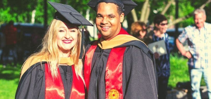 Two students graduating, wearing black graduation robes.