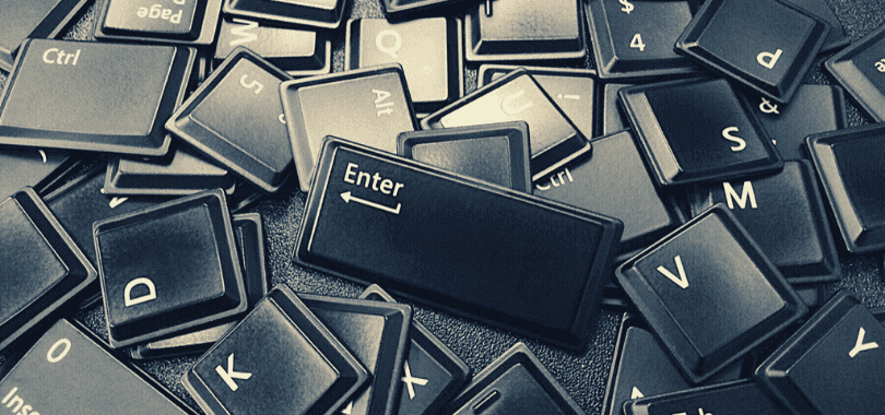 Keyboard keys scattered in a pile with the enter key sitting on top.