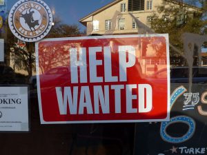 "Help Wanted" signage behind a glass wall.
