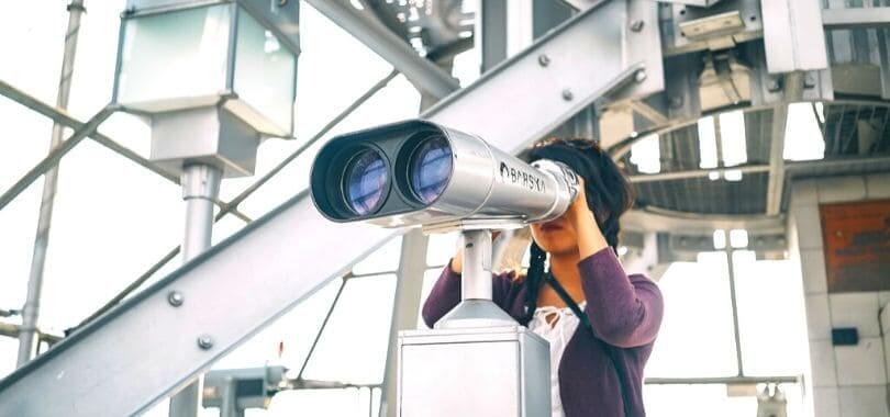 A student looking through a pair of binoculars.