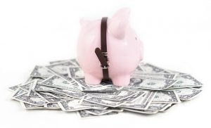 Piggy bank standing over paper dollar bills.