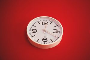 White wall clock against red background.
