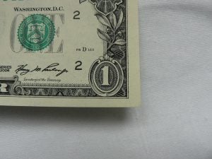 One dollar bill showing only the lower right corner.