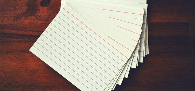 A stack of white note cards on a dark brown desk.