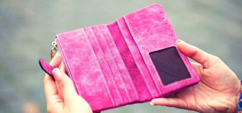 A person holding an empty pink wallet.