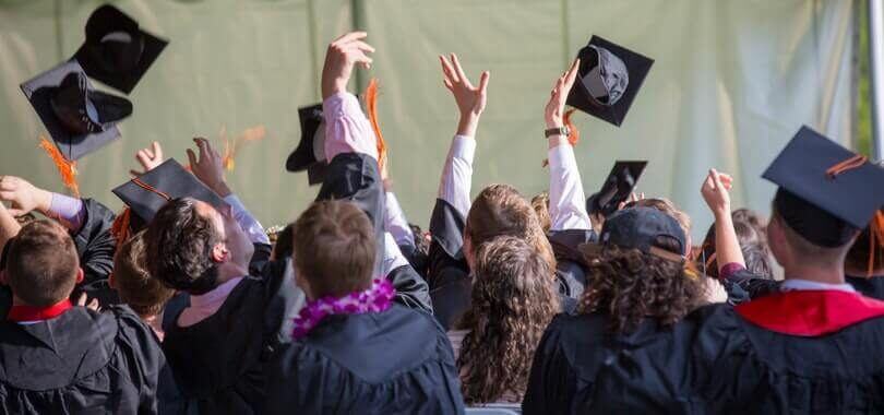 Graduating college students tossing their caps into the air.