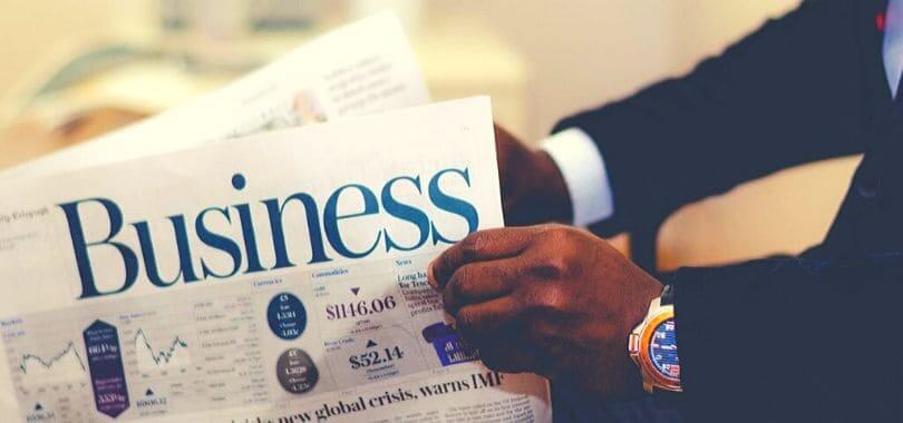Egy személy kezében egy újság, amire "business" van nyomtatva.
