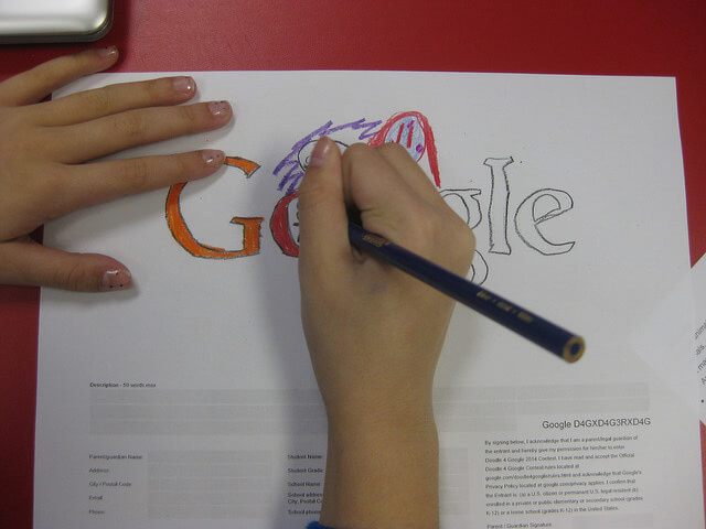 A hand doodling Google in white paper.