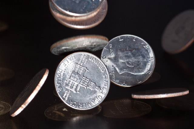 Close-up of coins falling onto a table.