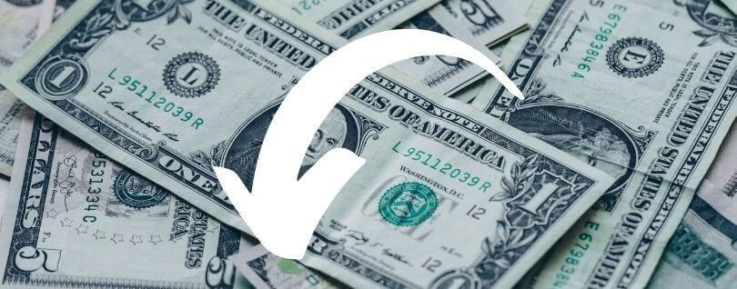 A pile of dollar bills with a white arrow pointing down superimposed on the image.