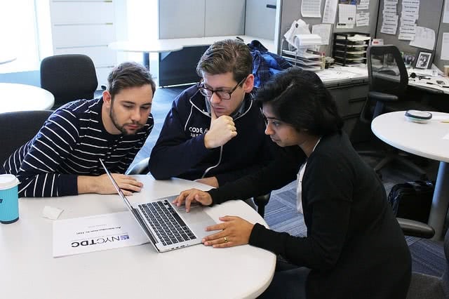 Three people having a meeting while looking at the laptop.