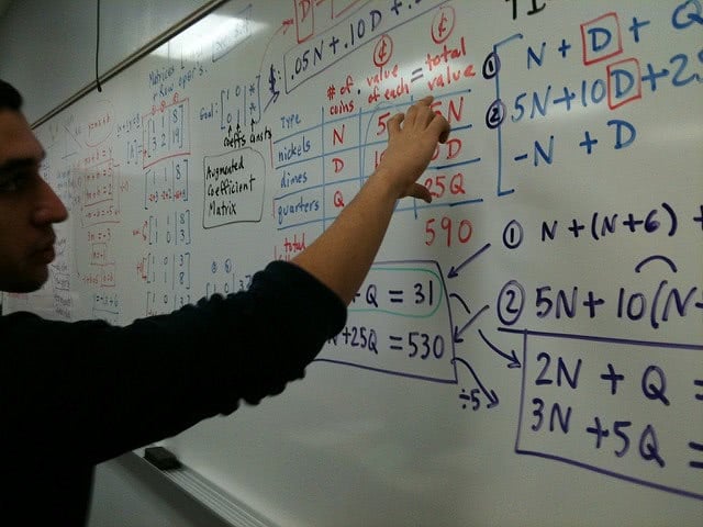 A student answers a math equation on the board.