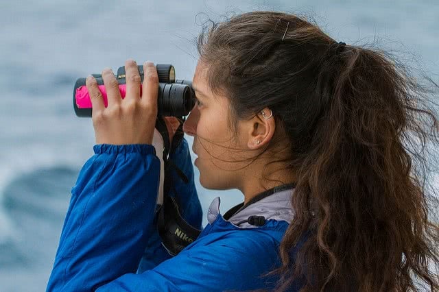 Side view of a girl looking through binoculars.