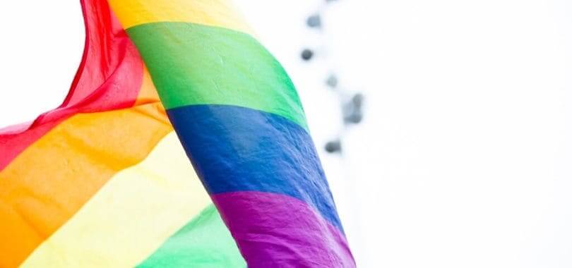 A rainbow flag fluttering against the sky.
