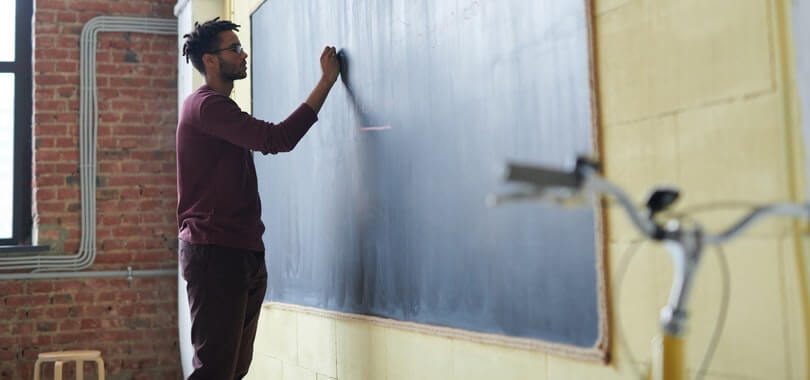 A person standing in front of a blackboard.