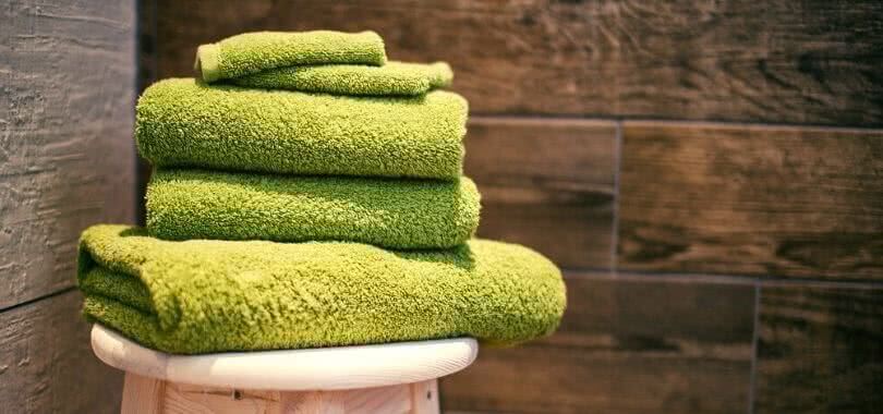 Green towels and cloths on a stool in a college dorm room.