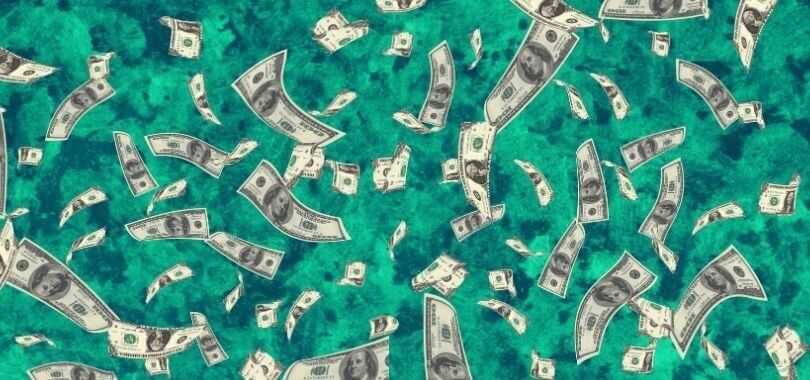 Money bills falling over a green marble background.
