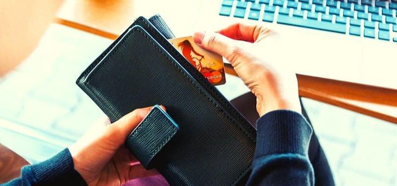 A person holding a wallet and pulling out a credit card.