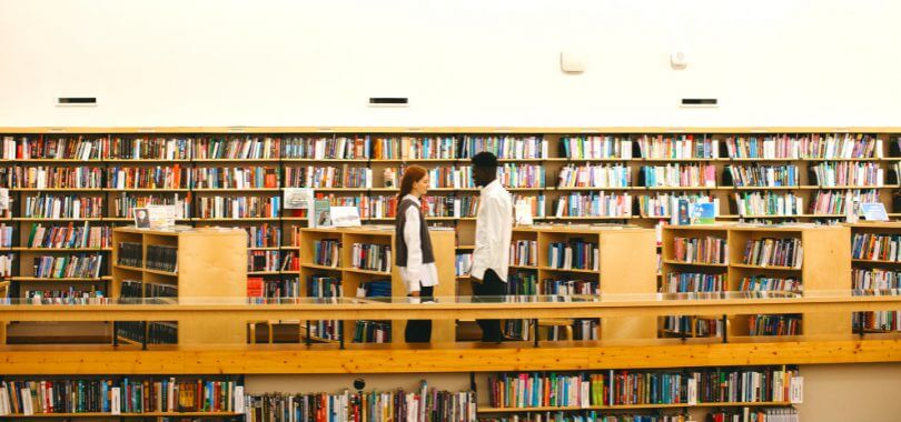 Two students standing in their liberal arts college library